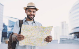 Cheerful man holding map, travel and tourism concept